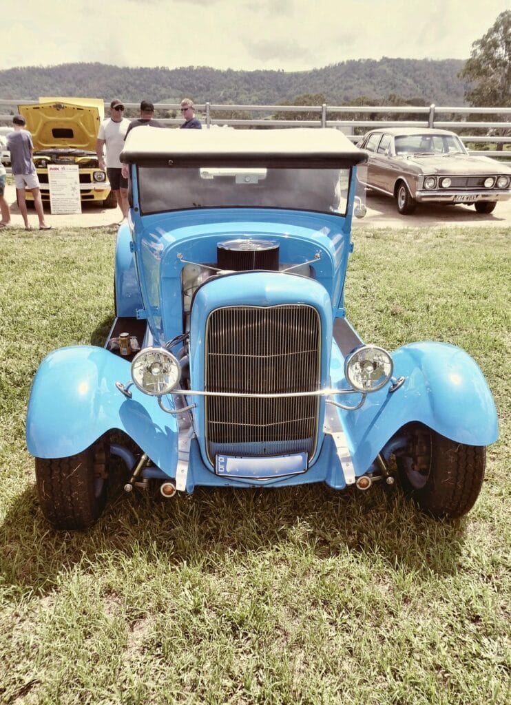 Blauwe klassieke oldtimer op grasveld tijdens evenement, passend bij een oldtimerverzekering voor klassieke auto’s.