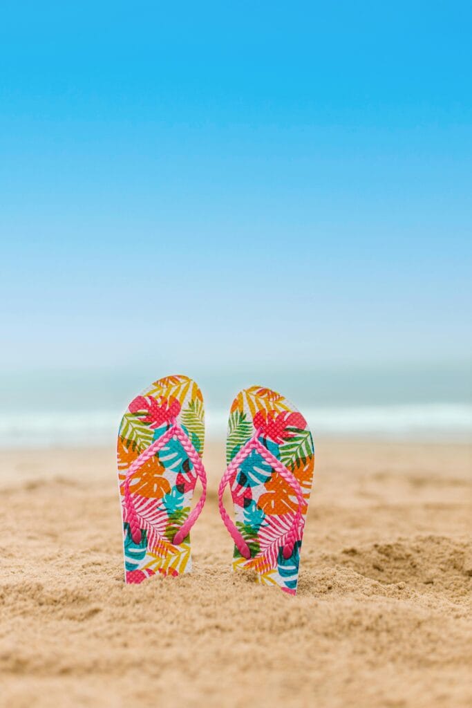 Strand slippers vakantie reisverzekering Slippers op het strand als symbool voor zorgeloos op vakantie met een reisverzekering