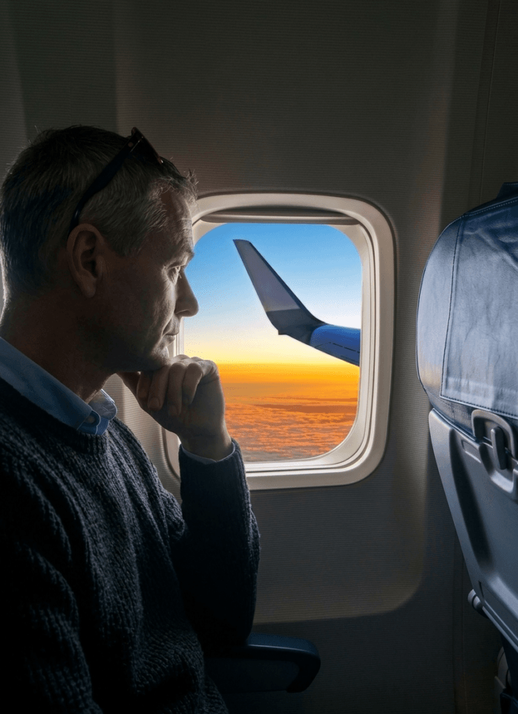 Man kijkt uit vliegtuigraam naar zonsondergang tijdens vlucht