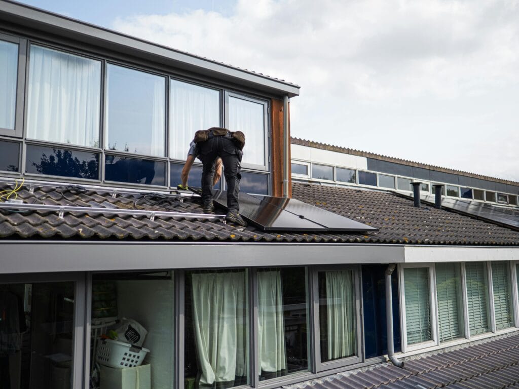 Monteur plaatst zonnepanelen op het dak van een woning