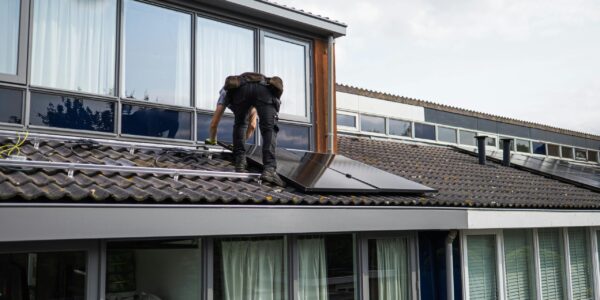 Monteur plaatst zonnepanelen op het dak van een woning